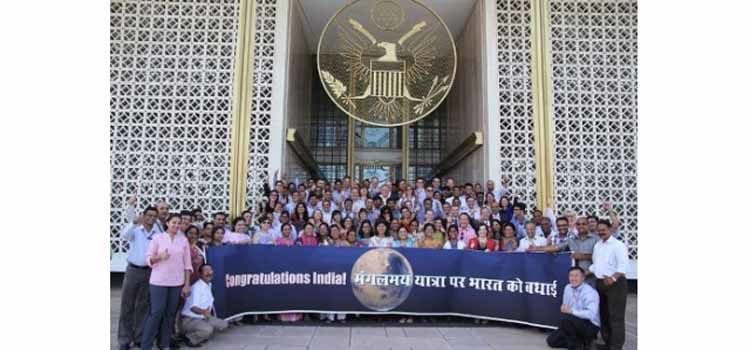 Large group of people with a banner outside of a building. (Photo Credit: State Department)