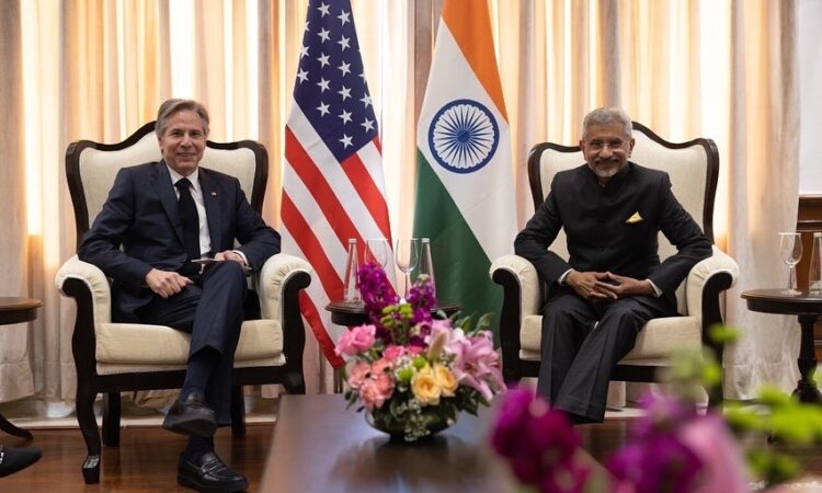 Secretary of State Antony Blinken and GOI Minister of External Affairs S.Jaishankar sitting next to each other. The U.S. and Indian flag are displayed behind them.